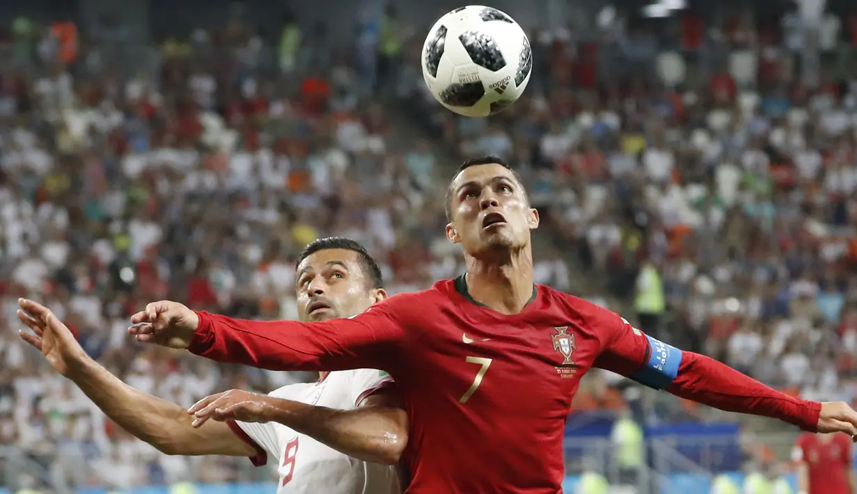 Duel pemain Portugal, Cristiano Ronaldo (kanan) dan pemain Iran, Omid Ebrahimi pada laga grup B Piala Dunia 2018 di Mordovia Arena, Saransk, Rusia, (25/6/2018). Portugal dan Iran bermain imbang 1-1. (AP/Pavel Golovkin)