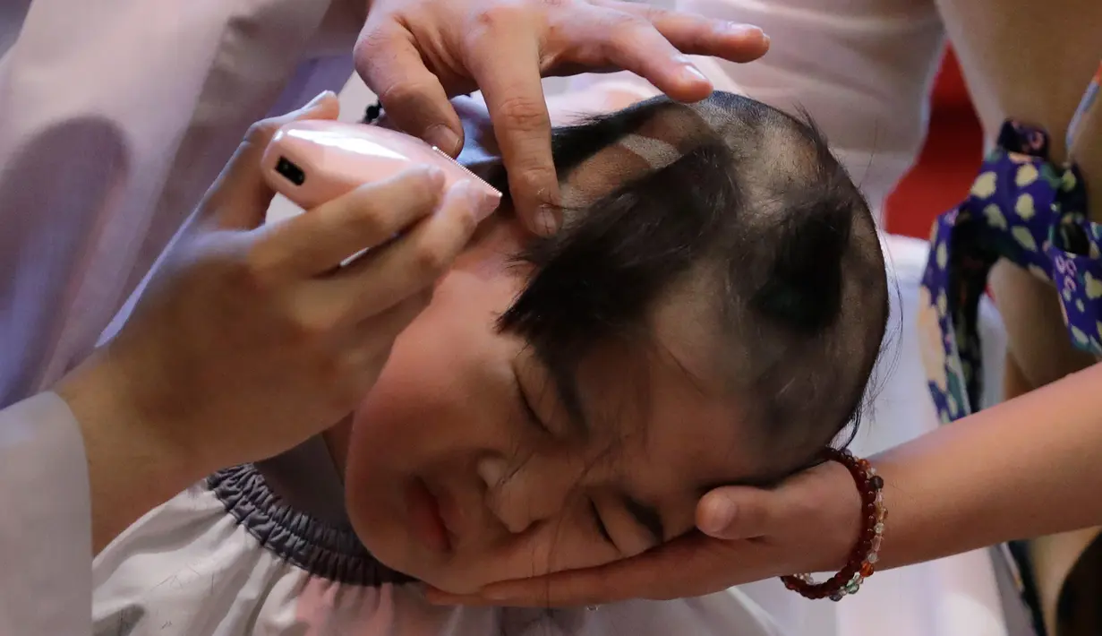 Reaksi bocah laki-laki saat rambutnya dicukur oleh seorang biksu dalam seremonial ulang tahun Buddha di kuil Jogye, Seoul, Korea Selatan, Rabu (2/5). Perayaan ulang tahun Buddha akan jatuh pada 22 Mei mendatang. (AP/Lee Jin-man)