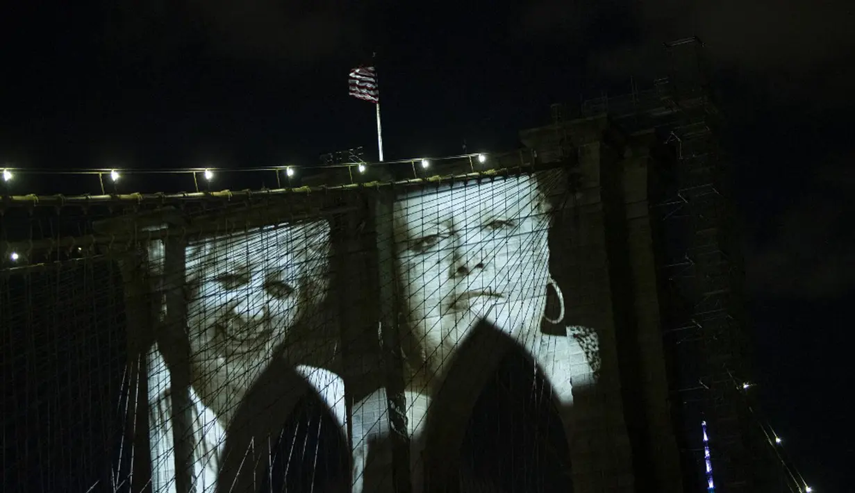 Gambar korban diproyeksikan pada Jembatan Brooklyn saat Hari Peringatan COVID-19 di Brooklyn, New York, Amerika Serikat, 14 Maret 2021. Upacara penghormatan yang digelar secara virtual itu dimulai dengan pertunjukan di Jembatan Brooklyn yang ikonik. (Kena Betancur/AFP)