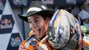 Pembalap dari tim Honda, Marc Marquez berpose sambil memegang helmnya saat merayakan kemenangannya pada MotoGP Amerika di Austin, Texas, (23/4). Valentino Rossi meraih Posisi kedua dan posisi ketiga ditempati Dani Pederosa. (AP Photo/Eric Gay)