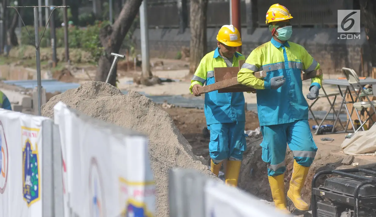 Pekerja mengangkut pasir untuk pembangunan pedestrian di Jalan Lapangan Banteng, Jakarta, Minggu (16/7). Pembangunan pedestrian ini bagian dari upaya meningkatkan fasilitas penunjang pejalan kaki di Ibu Kota. (Liputan6.com/Helmi Afandi)