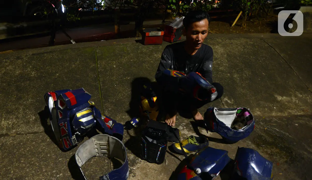 Seorang pria merapikan kostum robot kawasan Tomang, Jakarta, Selasa (14/9/2021). Abi (20) dan Nujum (48) mengenakan kostum robot Iron Man untuk mengais rejeki dan menghibur para pengendara dari kemacetan lalu lintas yang dilakukan sejak pandemi COVID-19. (merdeka.com/Imam Buhori)