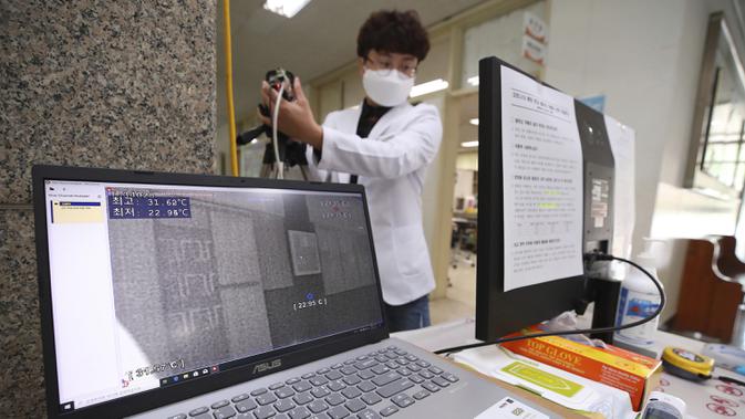Seorang guru memeriksa fungsi monitor kamera termal di sekolah menengah di Seoul, Korea Selatan, Senin (18/5/2020). Sekolah-sekolah di Korea Selatan secara bertahap akan mulai dibuka pada 20 Mei 2020. (Kim Do-hun/Yonhap via AP)