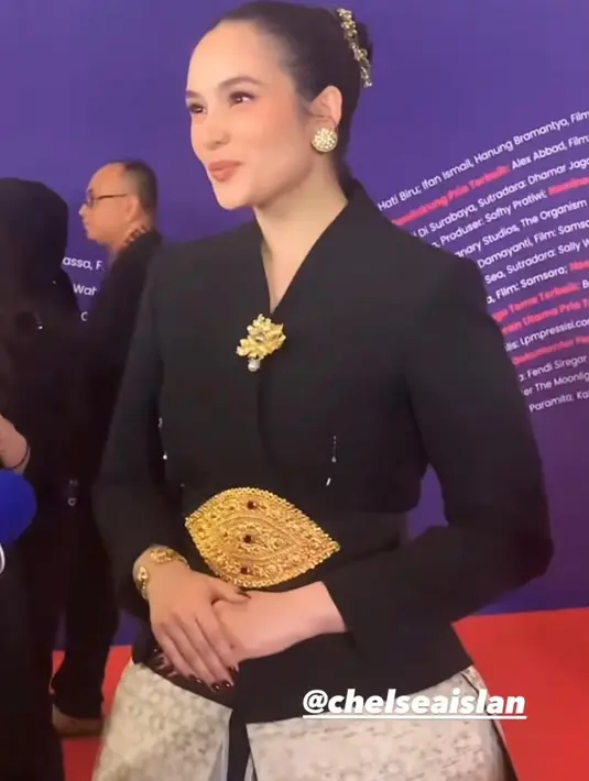 Chelsea Islan tak kalah memesona dalam balutan kebaya janggan yang dipadukan beberapa aksesori emas yang menambah impresi emas. Kebaya-nya kemudian dipaduan dengan songket warna silver dan rok layer.