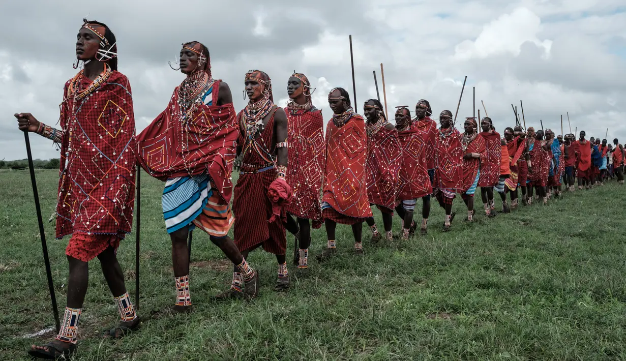 Sejumlah suku Masaai berjalan bersiap mengikuti kompetisi Olimpiade Maasai 2018 di Kimana, dekat perbatasan Kenya dengan Tanzania (15/12). Olimpiade Maasai  sudah diadakan setiap dua tahun sejak 2012. (AFP Photo/Yasuyoshi Chiba)