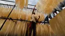 Seorang pekerja India menggantung helai bihun untuk dikeringkan di sebuah pabrik di Prayagraj, India pada 25 April 2020. Bihun diminati di kalangan Muslim ketika mereka berbuka puasa selama bulan suci Ramadan. (AP Photo/Rajesh Kumar Singh)