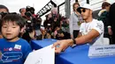Pembalap Mercedes Lewis Hamilton memberi tanda tangan kepada seorang bocah Jepang jelang Grand Prix F1 di Sirkuit Suzuka, Jepang (5/10). Sebelum bertanding pada 8 Oktober mendatang, Hamilton menyapa penggemar di Jepang. (AP Photo/Toru Takahashi)