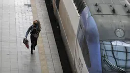 Seorang wanita yang mengenakan masker untuk membantu melindungi dari penyebaran virus corona berlari ke kereta menjelang liburan Chuseok atau Hari Thanksgiving versi Korea di Stasiun Kereta Seoul di Seoul, Korea Selatan, Selasa (29/9/2020). (AP Photo / Ahn Young-joon)