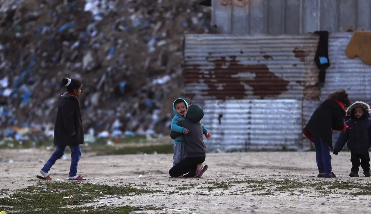 Anak-anak Palestina bermain di luar rumah mereka saat cuaca dingin di daerah kumuh di pinggiran kamp pengungsi Khan Younis, Jalur Gaza selatan pada Rabu, 19 Januari 2022. (AP Photo/Khalil Hamra)
