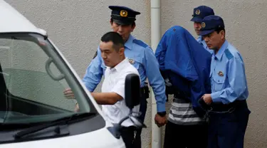 Pelaku pembantaian di sebuah panti penyandang cacat, Satoshi Uematsu (tengah) menutupi wajahnya dengan jaket saat dibawa petugas di kantor polisi Tsukui, Sagamihara, Prefektur Kanagawa, Jepang, Rabu (27/7). (REUTERS/Issei Kato)