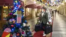 Seorang pria yang mengenakan masker dan sarung tangan untuk melindungi dari virus corona COVID-19 membawa belanjaan di GUM State Department Store, Moskow, Rusia, Senin (23/11/2020). Dekorasi untuk perayaan Natal dan Tahun Baru sudah menghiasi Rusia. (AP Photo/Pavel Golovkin)