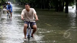 Curah hujan yang tinggi di Jakarta menyebabkan sejumlah kawasan terendam banjir. sejumlah warga melintasi jalan yang terendam air di sekitar Danau Sunter dengan menggunakan sepeda, Jakarta, Selasa (10/2/2015). (Liputan6.com/Faizal Fanani)