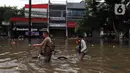 Warga melintasi banjir yang merendam kawasan Green Garden, Jakarta Barat, Selasa (25/2/2020). Hujan yang mengguyur kawasan Jakarta membuat kawasan tersebut tergenang banjir setinggi 60-80 cm. (Liputan6.com/Johan Tallo)