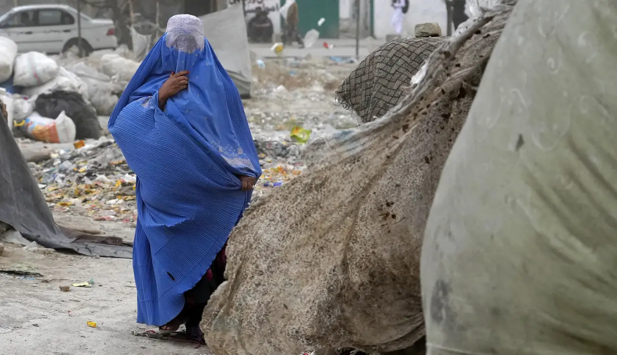 <p>Seorang perempuan yang mengenakan burqa berjalan di depan rumahnya di Kabul, Afghanistan, 8 Mei 2022. Taliban memerintahkan perempuan Afghanistan untuk mengenakan pakaian dari kepala hingga ujung kaki atau burqa tradisional di depan umum. (AP Photo/Ebrahim Noroozi)</p>
