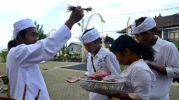 Seorang pemuka agama mencipratkan air suci pada beberapa warga Bali yang mendatangi pura di Jimbaran, Bali, Rabu (21/5/14). (AFP PHOTO/Sonny Tumbelaka)
