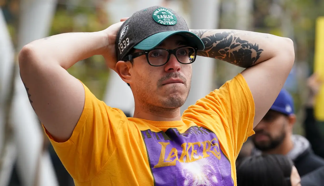 Fans LA Lakers tampak sedih usai Kobe Bryant meninggal dunia di Staples Center, Minggu (26/1/2020). Legenda basket NBA itu wafat dalam kecelakaan helikopter di Calabasas, California. (AFP/Rachel Luna)