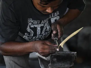 Seorang pandai besi membuat keris tradisional yang dikenal sebagai 'rencong' di sebuah bengkel di Sibreh, provinsi Aceh (5/10/2021). Rencong merupakan senjata khas Suku Aceh. (AFP/Chaideer Mahyuddin)