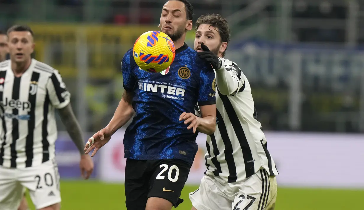 Gelandang Inter Milan, Hakan Calhanoglu mengontrol bola dari kawalan gelandang Juventus, Manuel Locatelli pada pertandingan final Piala Super Italia 2021 di Stadion San Siro di Milan, Italia, Kamis (13/1/2022). Inter Milan menang tipis atas Juventus 2-1 lewat perpanjangan waktu.  (AP Photo/Luca Brun