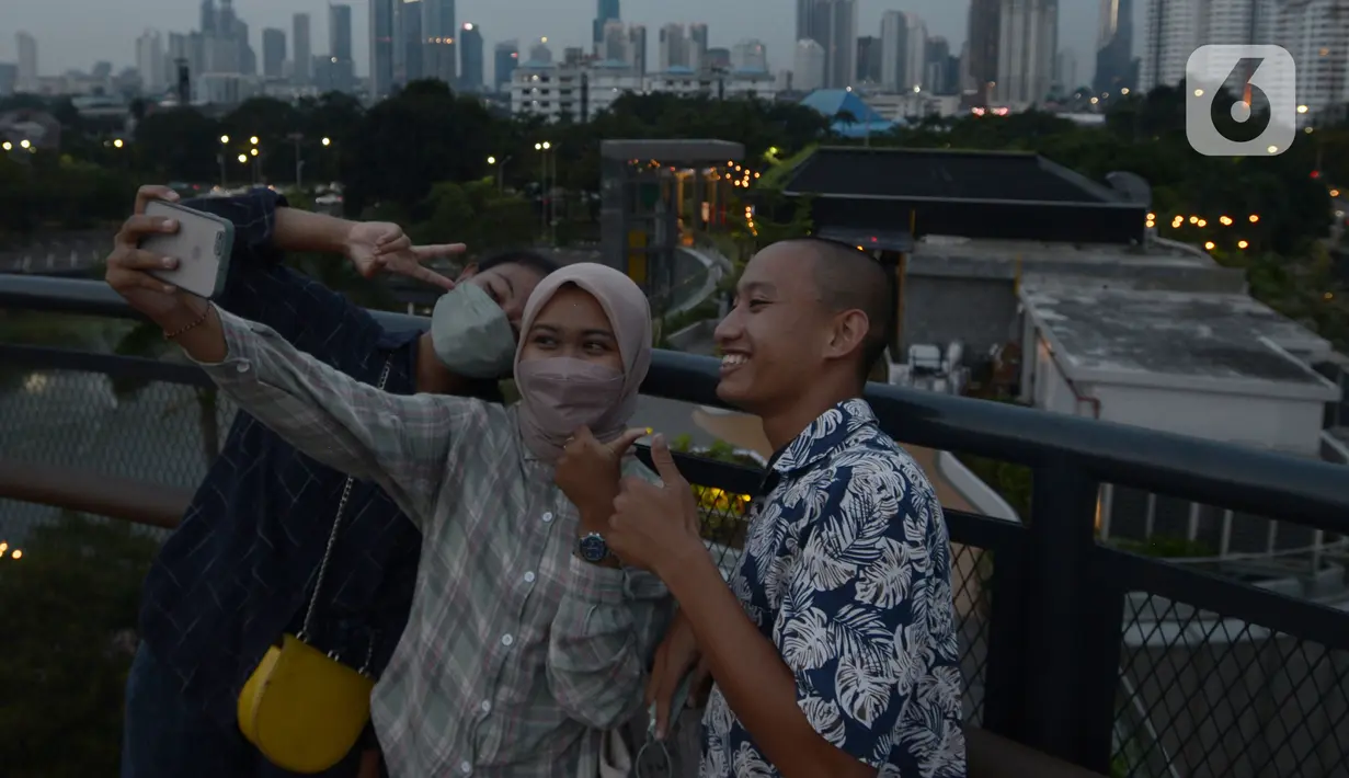 Pengunjung berfoto dari Skywalk Senayan Park, Jakarta, Rabu (29/12/2021). Kawasan yang menyajikan pemandangan lanskap perkotaan itu menjadi alternatif destinasi wisata Jakarta yang instagramble dengan spot foto yang beragam. (merdeka.com/Imam Buhori)