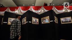 Pengunjung melihat karya foto dalam Pameran Foto Jurnalistik Warna-Warni Parlemen dengan tema Bangkit Lebih Cepat di loby Nusantara II DPR, Senayan, Jakarta, Senin (29/8/2022). Pada pameran Warna-warni Parlemen tahun ini terkumpul 1.200 karya foto, 101 di antaranya turut dipamerkan. (Liputan6.com/Johan Tallo)