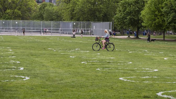 Pesepeda melewati lingkaran putih di Taman Trinity Bellwoods, Toronto, Kanada, Kamis (28/5/2020). Taman Trinity Bellwoods digambari lingkaran-lingkaran putih sebagai proyek uji coba untuk mendorong warga melakukan jaga jarak fisik (physical distancing) selama pandemi COVID-19. (Xinhua/Zou Zheng)