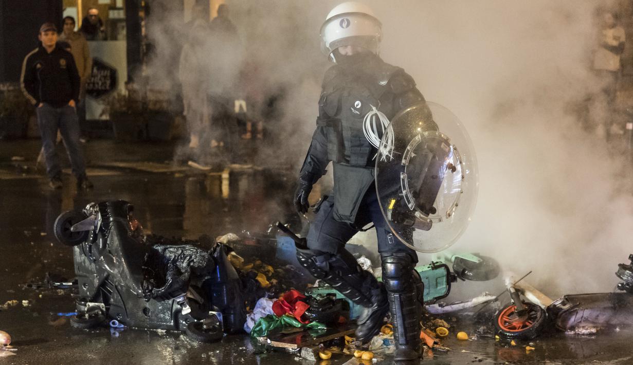 Untuk mencegah meluasnya kerusuhan tersebut, polisi melakukan tindakan keras terhadap para perusuh dengan menangkap serta menembakkan gas air mata agar massa bubar. (AP/Geert Vanden Wijngaert)