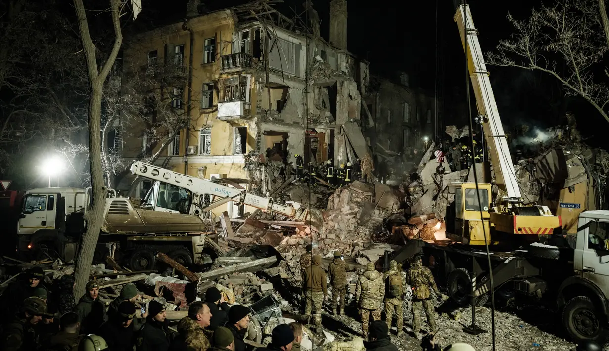 <p>Tim penyelamat memindahkan puing-puing untuk mencari korban selamat di gedung apartemen yang hancur terkena roket pada malam hari di pusat kota Kramatorsk, Ukraina timur, pada Rabu (1/2/2023). Sejumlah pejabat lokal Ukraina melaporkan bahwa satu gedung apartemen hancur total akibat serangan rudal itu. (Yasuyoshi CHIBA / AFP)</p>