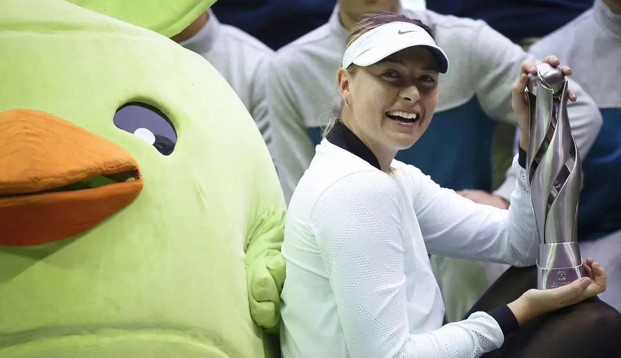 Maria Sharapova berpose dengan trofi setelah memenangkan pertandingan melawan Aryna Sabalenka di turnamen tenis Tianjin Open di Tianjin (15/10). ini merupakan gelar pertama Sharapova sejak kembali bertanding karena kasus doping. (AFP Photo/Wang Zhao)