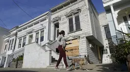 Pejalan kaki melewati rumah bergaya Victoria yang baru saja dijual di San Francisco, pada 14 Januari 2022. Rumah berusia 122 tahun yang sudah lapuk ini dipasarkan sebagai "rumah terburuk di blok terbaik" San Francisco terjual hampir 2 juta dollar AS atau sekitar Rp 28,6 miliar. (AP Photo/Jeff Chiu)