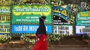 Pelayat melewati karangan bunga yang menghiasi jalan menuju rumah duka Presiden ke-3 RI BJ Habibie di Kuningan, Jakarta, Kamis (12/9/2019). Ucapan belasungkawa terus mengalir melalui karangan bunga dari berbagai elemen masyarakat. (Liputan6.com/Immanuel Antonius)