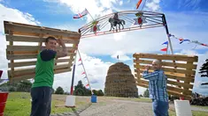 Dua orang pria membawa palet kayu yang akan disusun untuk membuat api unggun di Ballymacash, Lisburn, Irlandia (10/7). Api unggun raksasa ini dinyalakan setiap tahun di Irlandia Utara pada malam 11 Juli. (AFP Photo/Paul Faith)