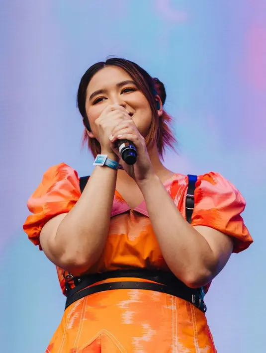 Penampilan Stephanie Poetri di panggung Head In The Clouds (HITC) Jakarta. Penyanyi besutan label musik 88rising ini tampil dengan dress cantik berwarna oranye. (Instagram/@hitcjakarta)