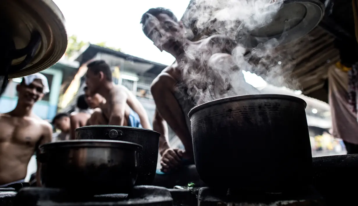 Narapidana memasak makan siang mereka di dalam penjara Quezon City di Manila, Filipina, 19 Juli 2016. Mereka memasak makanan dan berolahraga di sebelah kamar yang dipakai untuk mandi dan mencuci pakaian. (Noel Celis/AFP)