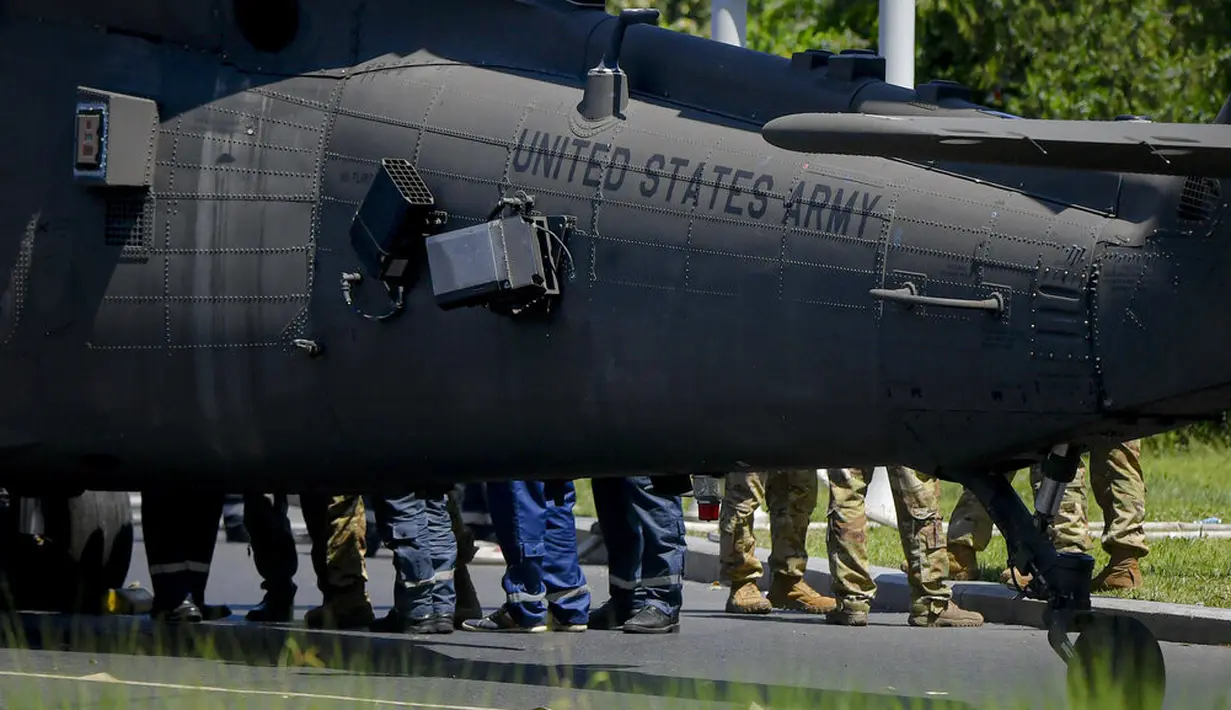Prajurit berjalan dengan helikopter Black Hawk militer AS setelah mendarat darurat di boulevard yang sibuk, di Bucharest, Rumania, Kamis (15/7/2201). Pendaratan itu merusak dua mobil setelah merobohkan dua tiang lampu namun tidak ada korban yang dilaporkan. (AP Photo/Andreea Alexandru)