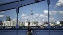 Seorang pria dengan sepeda berhenti di jembatan di Tokyo, Senin (28/9/2020). Ibukota Jepang mengonfirmasi lebih dari 70 kasus virus corona pada hari Senin. (AP Photo / Eugene Hoshiko)