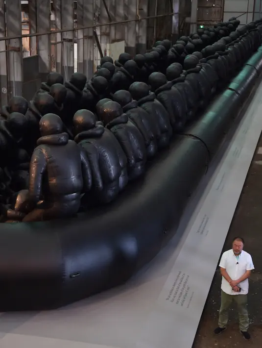 Seniman Ai Weiwei berpose di dekat karyanya yang berjudul "Law of the Journey 2017" pada sebuah preview pers Biennale ke 21 di Sydney (12/3). "Law of the Journey 2017" menggambarkan keadaan pengungsi di Eropa. (AFP Photo/Peter Parks)