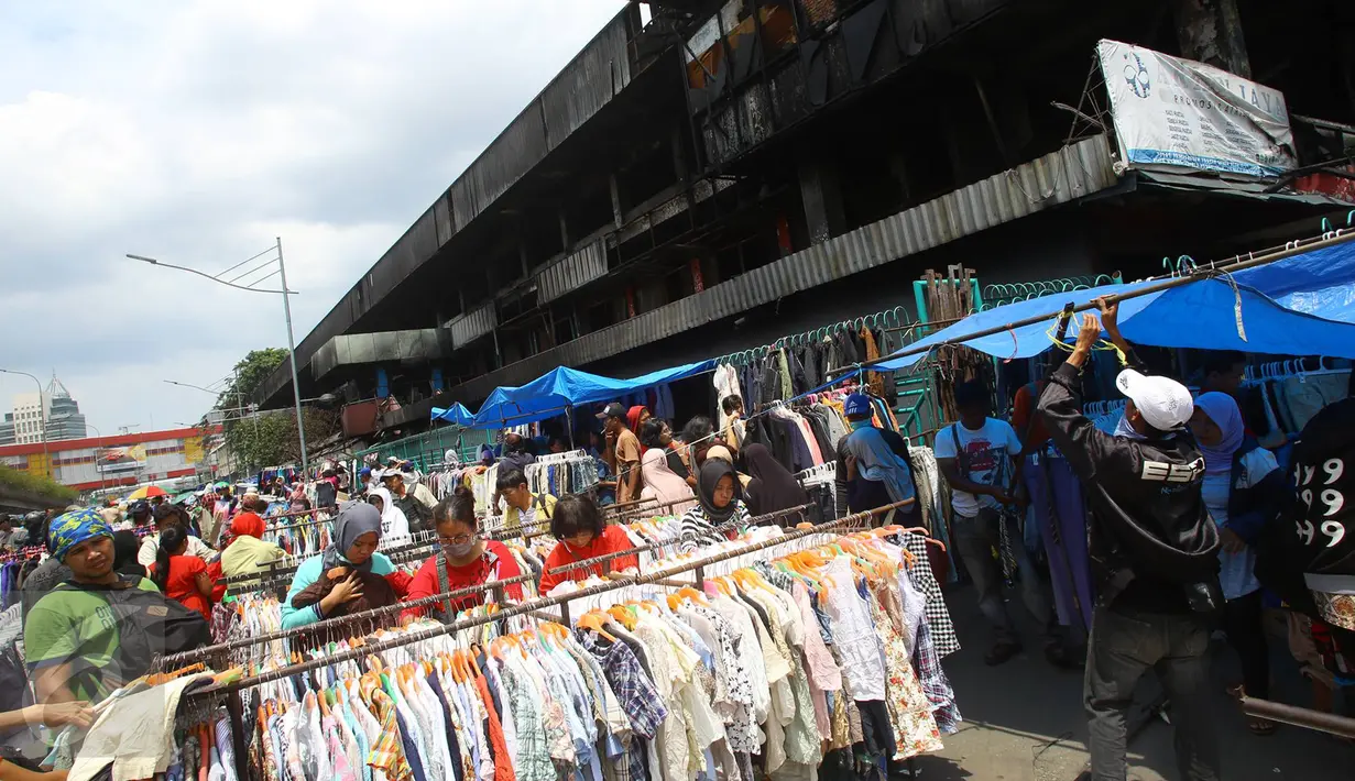 Pembeli melihat barang dagangan di kawasan Pasar Senen, Jakarta, Senin (23/1). Pascakebakaran beberapa hari lalu, para pedagang terpaksa berjualan di luar gedung, meskipun menutup jalan dan mengganggu arus lalu lintas. (Liputan6.com/Immanuel Antonius)