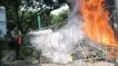 Polisi memadamkan karangan bunga yang dibakar oleh orang yang diduga menjadi provokasi saat aksi Hari Buruh di Jalan Medan Merdeka Barat, Jakarta, Senin (1/5). (Liputan6.com/Yoppy Renato)