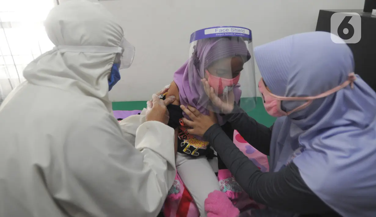 Dokter dengan Alat Pelindung Diri menyuntikkan vaksin cacar pada anak di Rumah Vaksinasi Sawangan, Depok, Selasa (16/6/2020). Orang tua diminta tidak menunda pemberian imunisasi pada anak-anak yang masih harus menerima imunisasi lengkap, meskipun di tengah pandemi Covid-19. (merdeka.com/Arie Basuki)