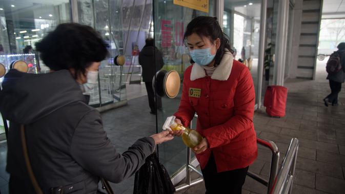 Petugas menyemprotkan sanitizer ke pengunjung di dalam Pyongyang Department Store No. 1, Korea Utara (28/12/2020). Meski Korea Utara melaporkan nol kasus Covid-19, pemerintahan Pyongyang tetap menerapkan standar protokol kesehatan guna mencegah penyebaran Covid-19. (AFP/Kim Won Jin)