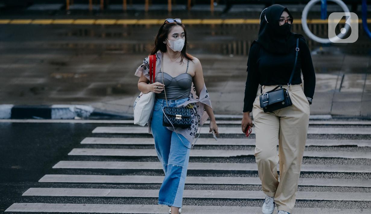 Dua remaja wanita berjalan melintasi zebra cross di Taman Sudirman, Jakarta, Rabu (6/7/2022). Tempat ini viral karena jadi ajang adu fashion anak Citayam, Bekasi hingga Bojong Gede. Mereka mengenakan kemeja flanel oversize, celana model 90-an seperti boot cut atau cutbray, sneakers klasik, dan tentu saja topi. (Liputan6.com/Faizal Fanani)