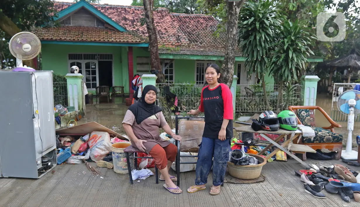 Keluarga ibu Haji Mamah Rusmahwati berpose di depan kediamannya Desa Sumber Urip Pebayuran, Kabupaten Bekasi, Jawa Barat, Senin (22/2/2021). Banjir merenda keluarga tersebut merapikan barang-barang dan bersihkan rumah yang sudah surut. (Liputan6.com/Herman Zakharia)