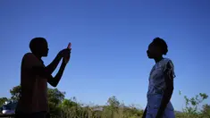 Seorang penduduk mengambil foto saudaranya dari ponselnya di Kalunga quilombo, di daerah pedesaan Cavalcante di negara bagian Goias, Brasil, Senin (15/8/2022). Nenek moyang penduduk desa Kalunga quilombo menetap di sana sebagai budak yang melarikan diri lebih dari 200 tahun yang lalu. (AP Photo/Eraldo Peres)