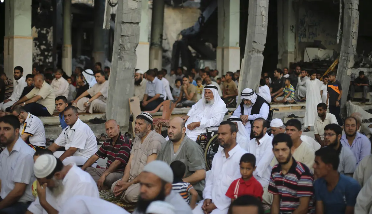 Warga muslim Palestina mendengarkan khotbah saat melaksanakan salat Idul Fitri di salah satu masjid yang rusak parah akibat serangan militer Israel di Rafah, Jalur Gaza, Senin (28/7/14).(REUTERS/Ibraheem Abu Mustafa)