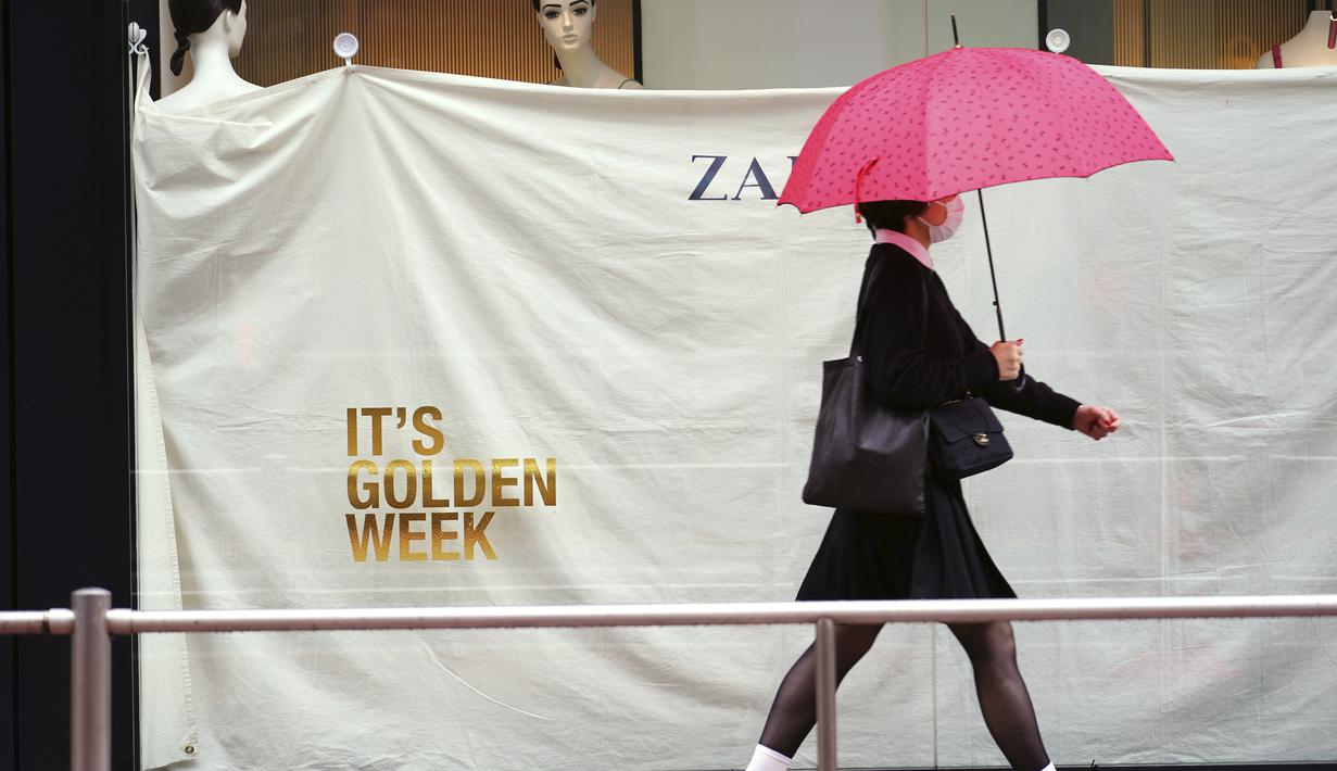 Seorang wanita yang mengenakan masker pelindung untuk membantu mengekang penyebaran virus corona berjalan di dekat jendela toko pakaian pada awal liburan "Minggu Emas" Jepang di distrik Shibuya, Tokyo, Kamis (29/4/2021). (AP Photo/Eugene Hoshiko)