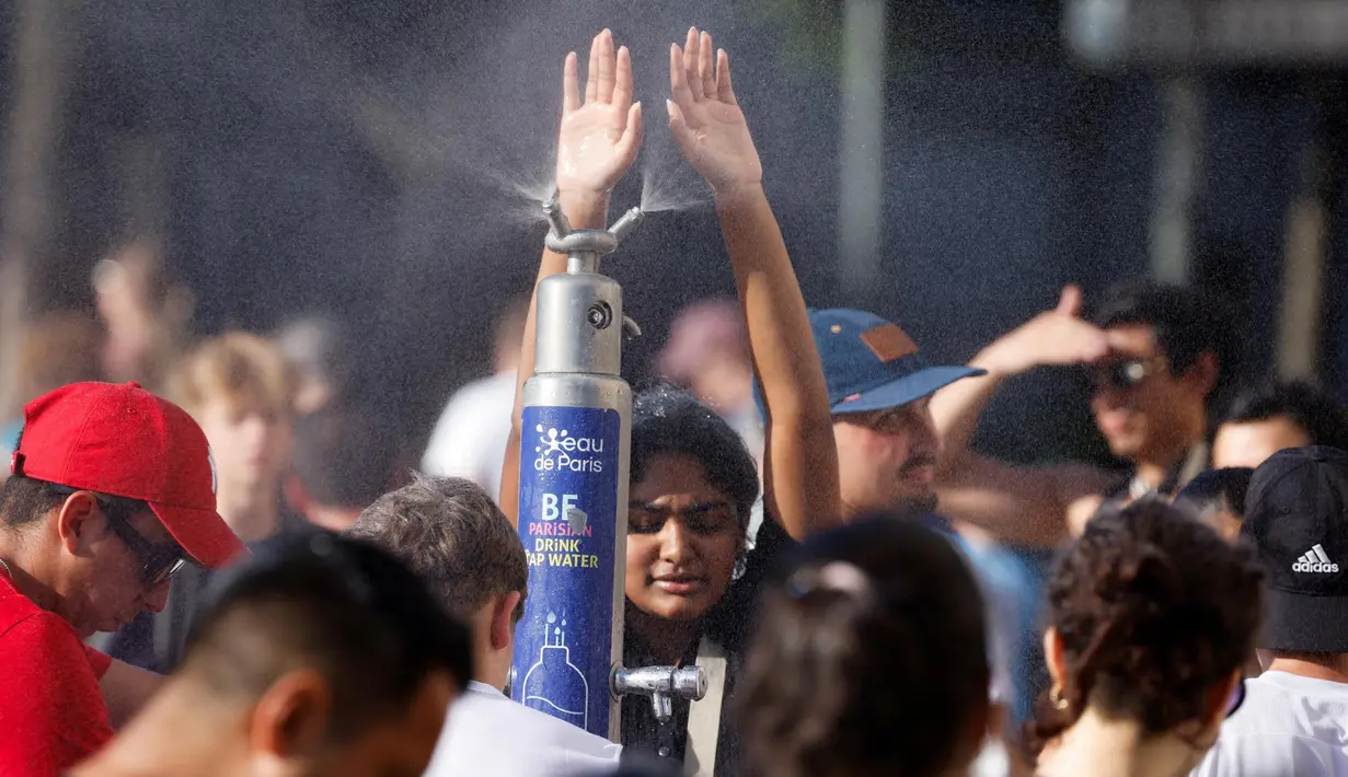 Orang-orang menyegarkan diri di sebuah taman publik selama gelombang panas di Paris, pada 30 Juni 2025. (Ludovic MARIN/AFP)