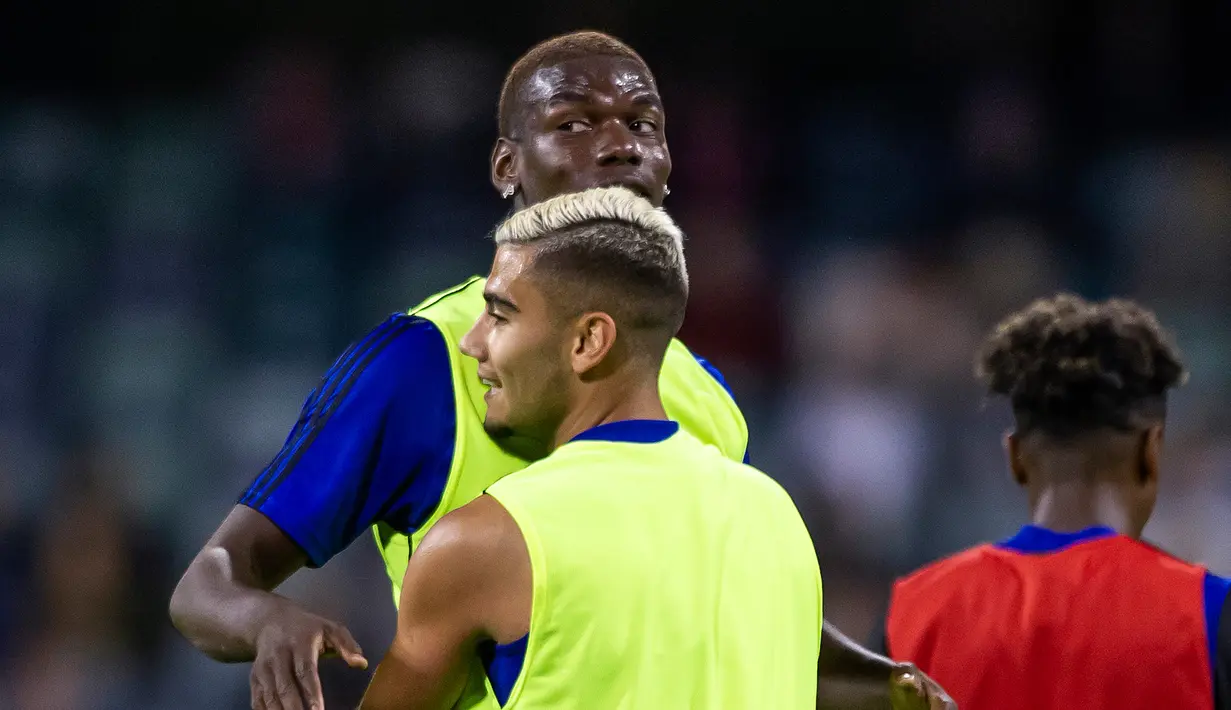 Gelandang Manchester United, Paul Pogba berbincang dengan rekannya Andreas Pereira selama sesi latihan terbuka jelang pertandingan tur pramusim melawan Perth Glory di Stadion Optus, Perth (11/7/2019). MU dijadwalkan menggelar tur pramusim di Australia, Tiongkok, dan Singapura. (AFP Photo/Tony Ashby)