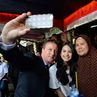 Dalam kunjungannya, David Cameron ditemani penyanyi cantik Maudy Ayunda. Mereka melakukan foto selfie bersama ibu pemilik warung. (via dailymail.co.uk)