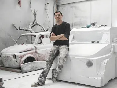 Seniman Italia, Nazareno Biondo berpose dengan replika mobil Fiat 500 berbahan dasar marmer Carrara pahatannya di Cafasse, dekat Turin, Italia, Rabu (16/5). (MARCO BERTORELLO/AFP)