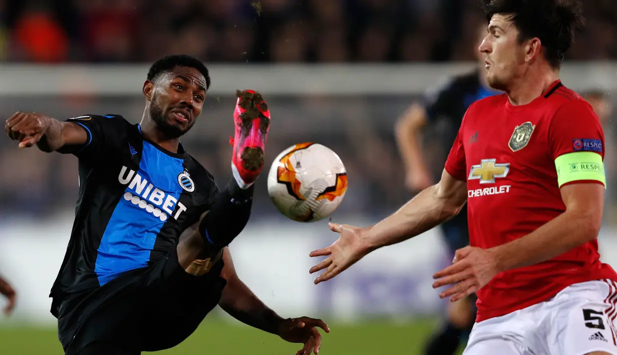 Pemain Club Brugge,  Emmanuel Bonaventure (kiri) berebut bola dengan bek Manchester United, Harry Maguire dalam leg pertama babak 32 besar Liga Europa di Jan Breydelstadion, Kamis (20/2/2020). Manchester United gagal meraih hasil maksimal usai ditahan imbang Club Brugge 1-1. (JOHN THYS / AFP)